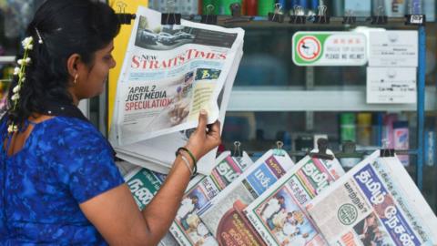 A woman reads a newspaper in Tanjung Malim, Malaysia, March 2018.