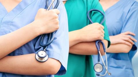 Three nurses and doctors stand side by side