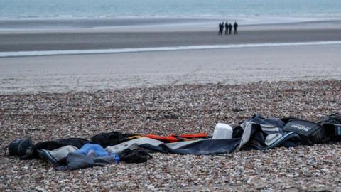 Remains of damaged migrants' inflatable boat and personal belongings left by migrants on the beach near Wimereux, France, 25 November 2021