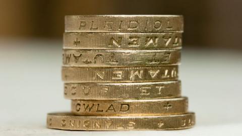 A stack of one pound coins sitting on a two pound coin