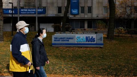 Two people walk outside the Hospital for Sick Children in Toronto, Canada.