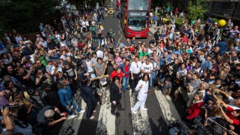 Beatles fans walks across Abbey Road in London.