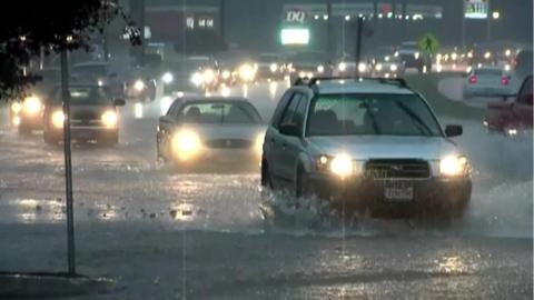 Image shows cars travelling through flooded roads