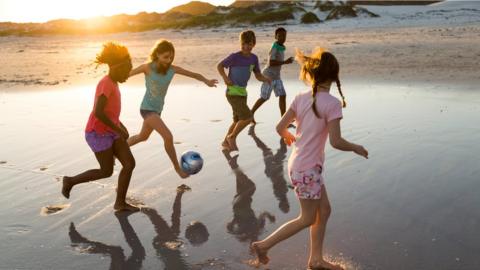 Children playing football on the beach