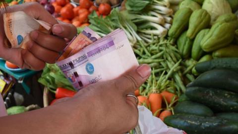 A customer buys vegetables at a market in Manila, the Philippines.