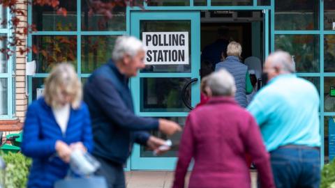 Two couples speak to each other outside a Stormont assembly election polling station at a primary school