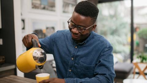 A man pours hot water from a kettle