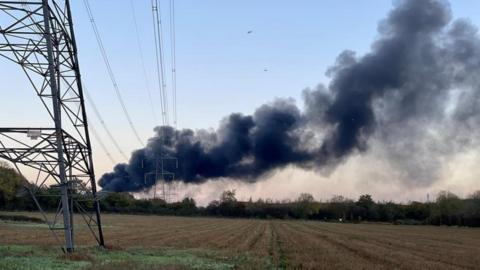 Black smoke in the sky over a field next to the quarry