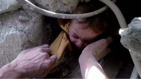 Child being pulled from rubble in Syria