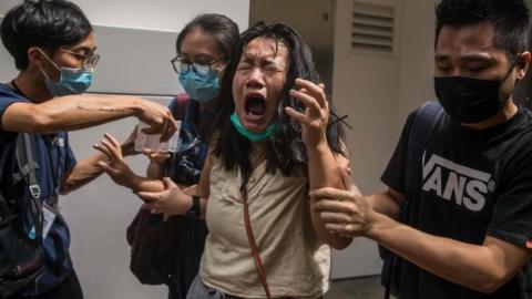 A woman reacts after she was hit with pepper spray deployed by police