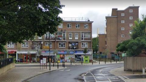 Google Street View image of shops and flats at a junction of Thessaly Road.