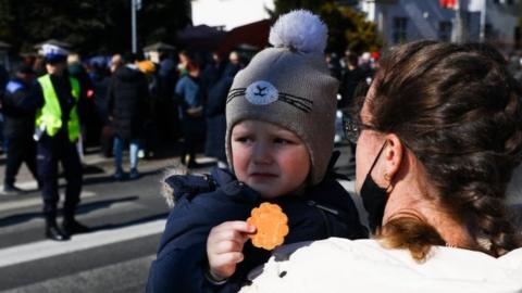 Ukrainian refugees queue outside the embassy in Krakow, Poland