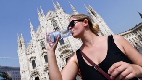 A woman drinks water in hot Milan, 26 June
