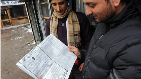Men reading a newspaper in Srinagar