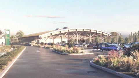 A proposed digital rendering of what the service station will look like. It has a rounded roof and lots of pillars holding it up, a large car park and surrounded by greenery