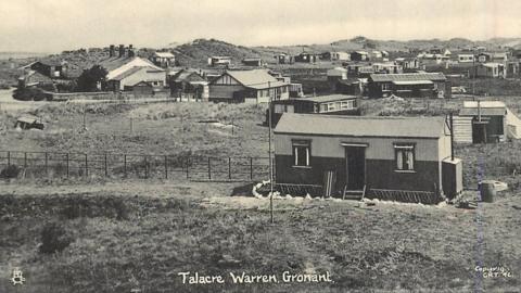 Black and white photo shows chalets among the sand dunes