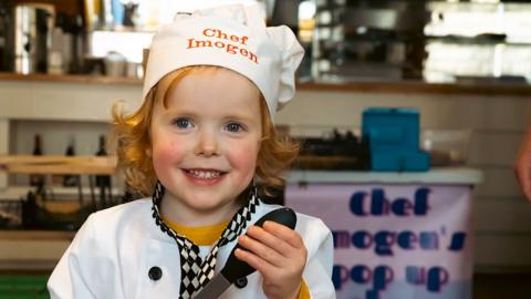 Imogen smiling at camera in front of stall