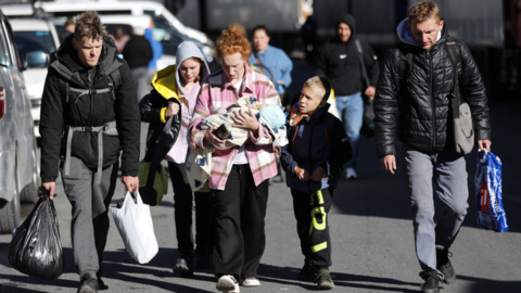 Young man, a woman with a baby and children walk to cross the border from Russia into Georgia. Photo: 27 September 2022