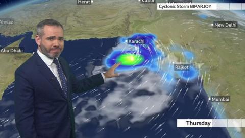 Ben Rich stands in front of a weather map showing the track of Cyclone Storm Biparjoy near India and Pakistan