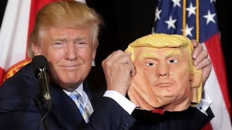 Donald Trump holds up a Donald Trump mask
