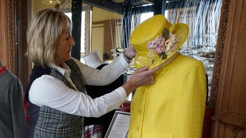 Assistant curator Sarah Hoare adjusts outfits worn by Queen Elizabeth II whilst at Balmoral as they go on display in the Castle Ballroom at the opening of Life at Balmoral