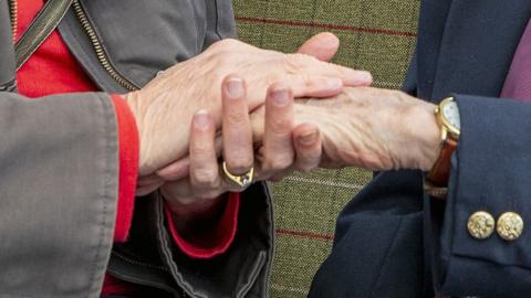 Two people's hands clasped together