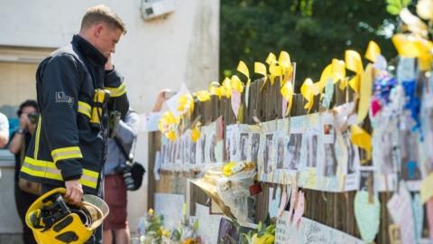 Firefighter at floral tributes near Grenfell Tower