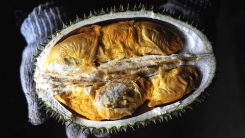 A vendor displays the cross section of a durian fruit at a roadside shop in Karak