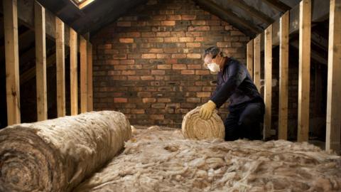 Man installing insulation in a loft