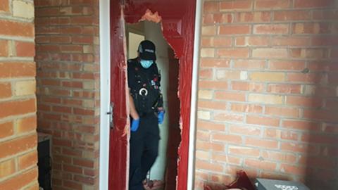 Police officer inspects a smashed up front door