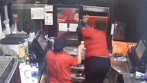Woman leans out through drive through window as car speeds away