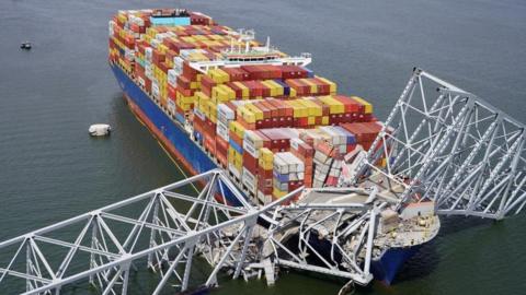 An aerial view of the Dali cargo ship, which crashed into a bridge spanning the entrance to the Port of Baltimore. The bridge is seen collapse around part of the vessel.