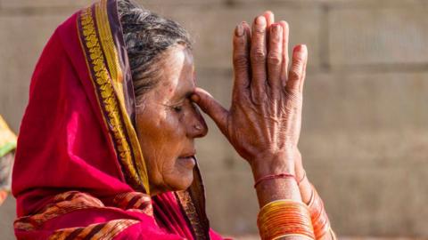 A female pilgrim is praying at the holy river Ganges at Dashashwamedh Ghat, Main Ghat, in the suburb Godowlia.