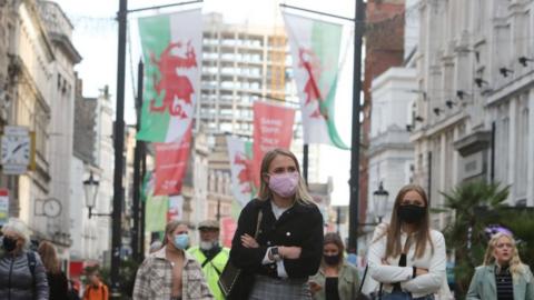 Women in masks in front of Welsh flags