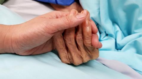 nurse holding patient's hand in hospital