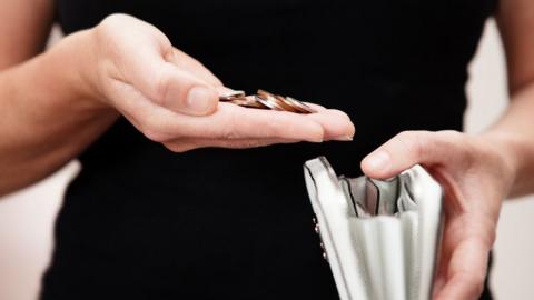 Woman with coins in hand with purse - stock photo