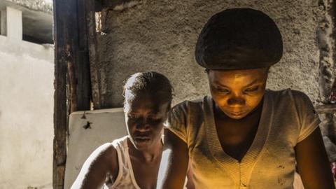 Two women clean rice at one of the slum's restaurants