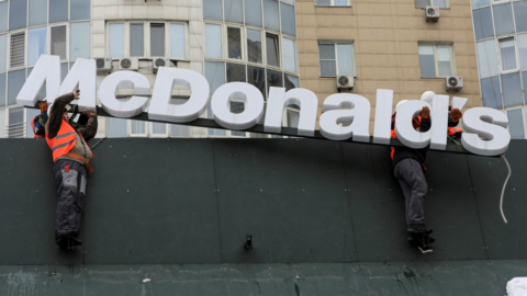 Workers remove the logo signage from a restaurant of McDonald's in Kazakhstan