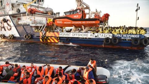 Members of Maltese NGO MOAS help people to board a small rescue boat during a rescue operation of migrants and refugees by the Topaz Responder ship run by Maltese NGO Moas and the Italian Red Cross, on November 5, 2016