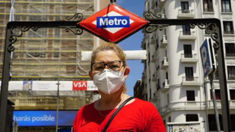 A woman wearing a mask outside a metro station in Madrid