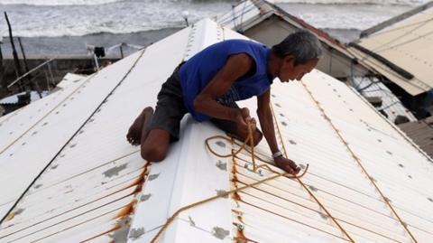 Man tying down his roof