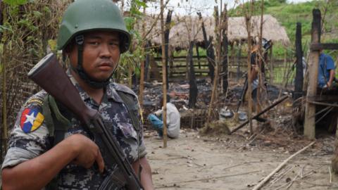 A Myanmar border guard police officer stands guard in front of the remains of a house burned down in a clash between suspected militants and security forces in Tin May village, Buthidaung township, northern Rakhine state, Myanmar 14 July 2017