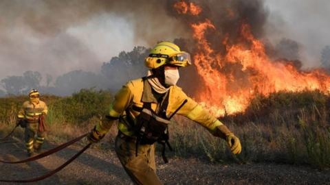 Firefighters in front of large fire