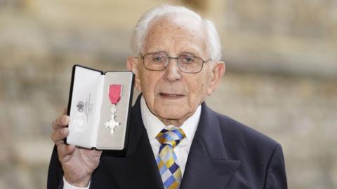 Harry Olmer holding up his MBE