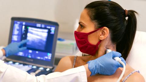 Stock image of a woman undergoing a thyroid ultrasound scan