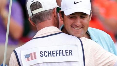 Scottie Scheffler is congratulated by his caddie after winning the Players Championship