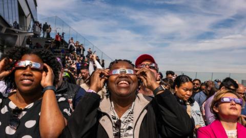 People watch a partial solar eclipse on the observation deck of Edge at Hudson Yards
