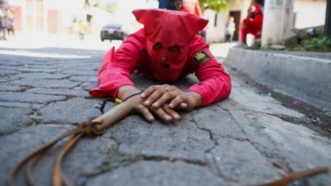 A man dressed as a demon lies on the ground as he participates in a ceremony known as Los Talciguines, as part of religious activities to mark the start of the Holy Week in Texistepeque, El Salvador, April 11, 2022.