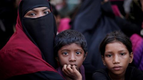 A Rohingya refugee family sits in a queue as they wait to receive humanitarian aid at Kutupalong refugee camp near Cox's Bazar