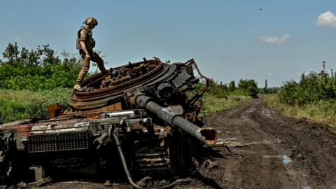 A Ukrainian serviceman inspects a destroyed Russian tank in the recently liberated village of Novodarivka, amid Russia's attack on Ukraine, in Zaporizhzhia region, Ukraine July 21